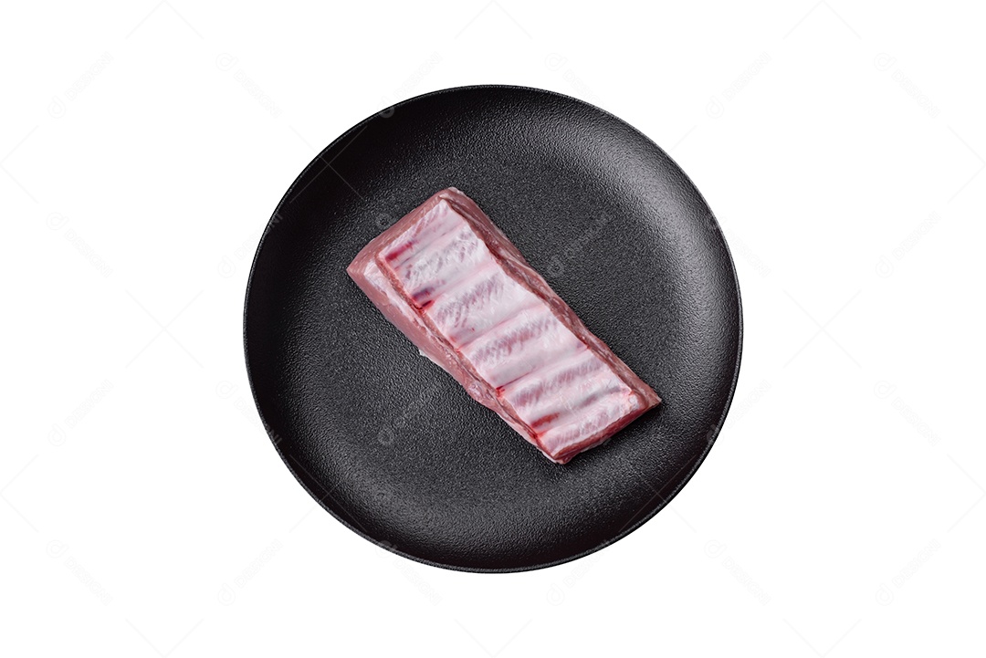 Costelas de porco cruas com sal, especiarias e ervas em fundo de concreto texturizado