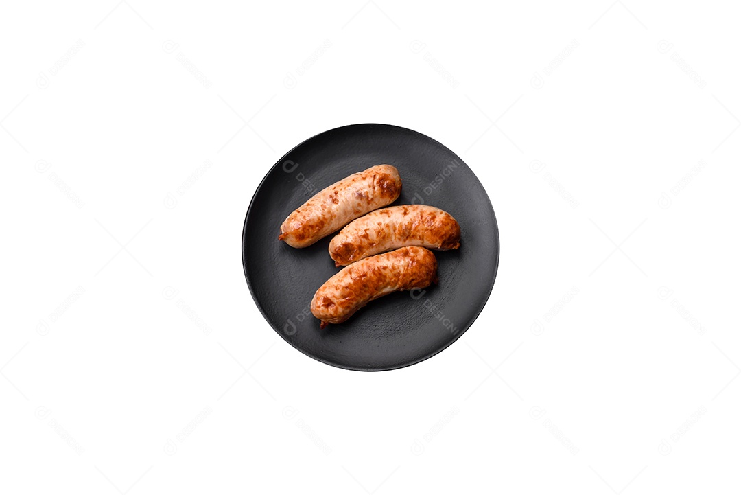 Deliciosas salsichas grelhadas suculentas com sal, especiarias e ervas numa placa cerâmica sobre um fundo escuro de concreto