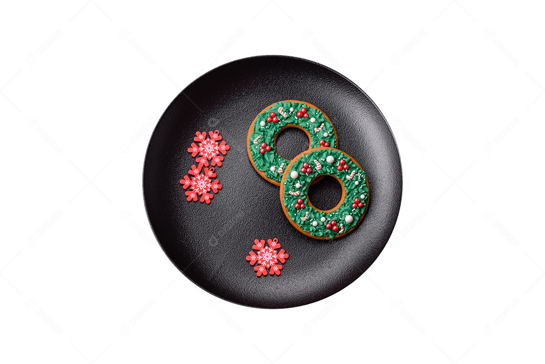 Lindos biscoitos de gengibre caseiros coloridos de Natal ou Ano Novo em uma placa cerâmica sobre um fundo escuro de concreto