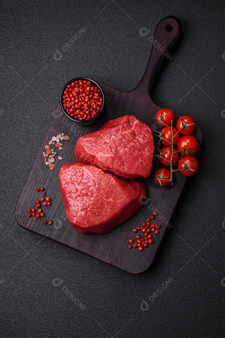 Fatias frescas e suculentas de carne crua com sal e especiarias sobre um fundo escuro de concreto