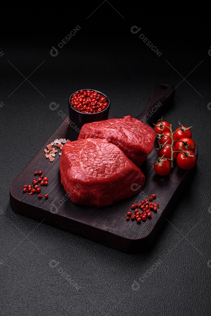 Fatias frescas e suculentas de carne crua com sal e especiarias sobre um fundo escuro de concreto