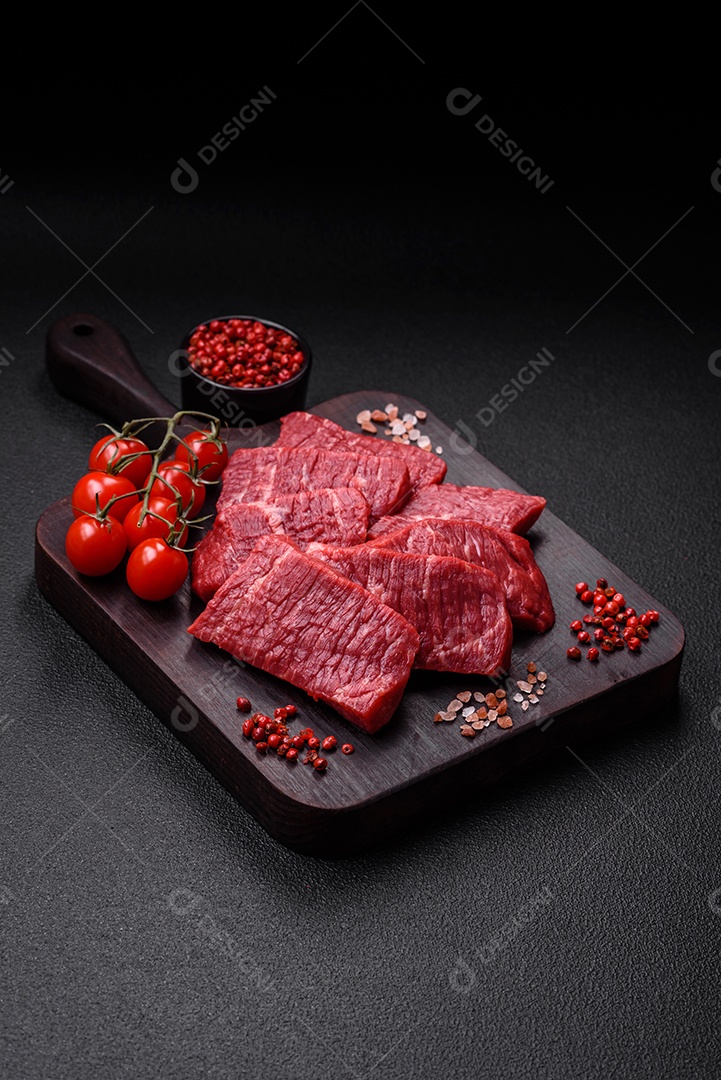 Fatias frescas e suculentas de carne crua com sal e especiarias sobre um fundo escuro de concreto
