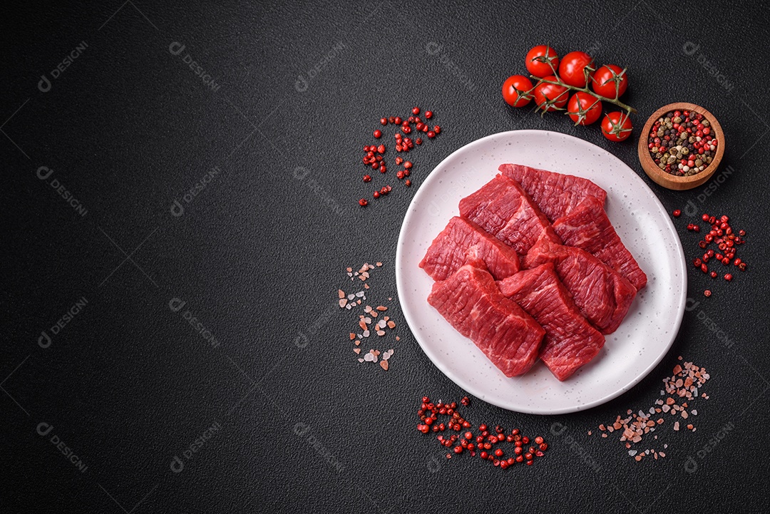 Fatias frescas e suculentas de carne crua com sal e especiarias sobre um fundo escuro de concreto