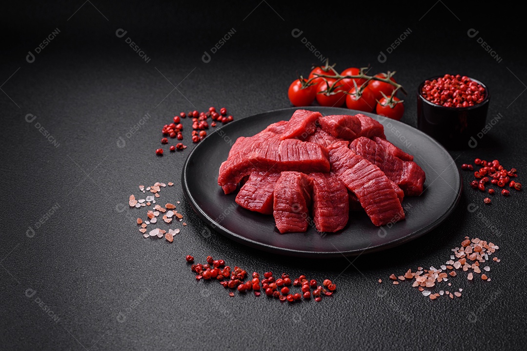Fatias frescas e suculentas de carne crua com sal e especiarias sobre um fundo escuro de concreto