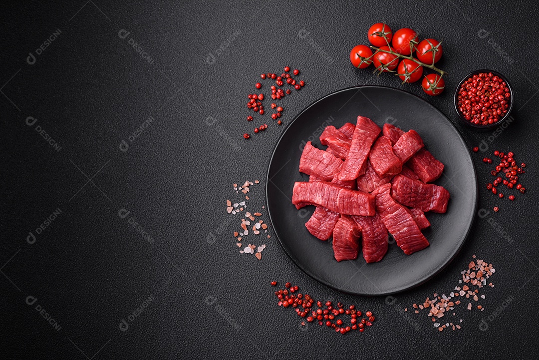 Fatias frescas e suculentas de carne crua com sal e especiarias sobre um fundo escuro de concreto