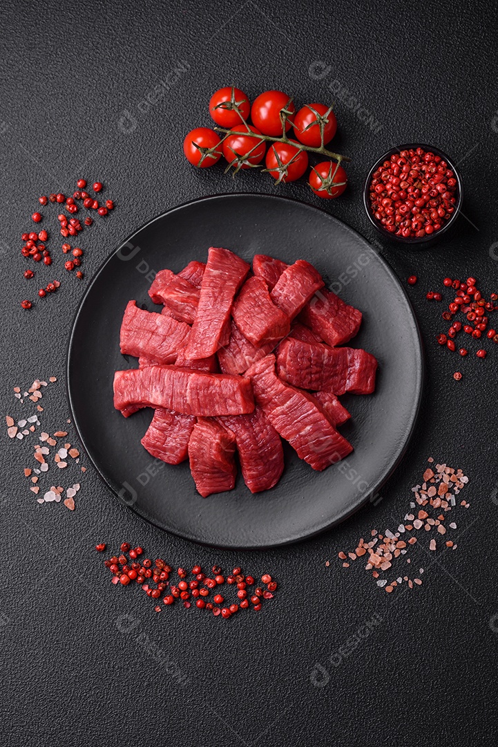 Fatias frescas e suculentas de carne crua com sal e especiarias sobre um fundo escuro de concreto