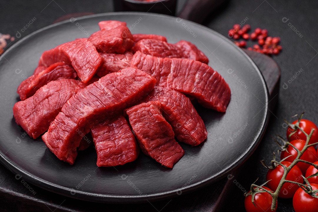 Fatias frescas e suculentas de carne crua com sal e especiarias sobre um fundo escuro de concreto