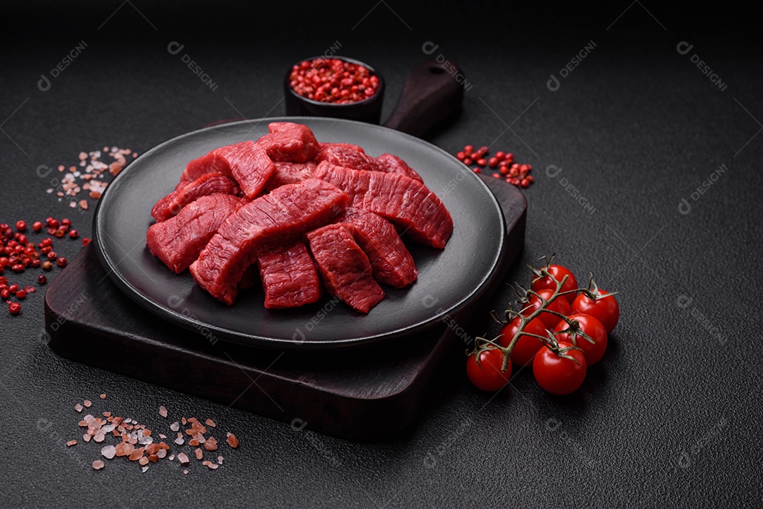 Fatias frescas e suculentas de carne crua com sal e especiarias sobre um fundo escuro de concreto
