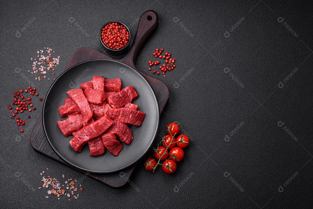Fatias frescas e suculentas de carne crua com sal e especiarias sobre um fundo escuro de concreto
