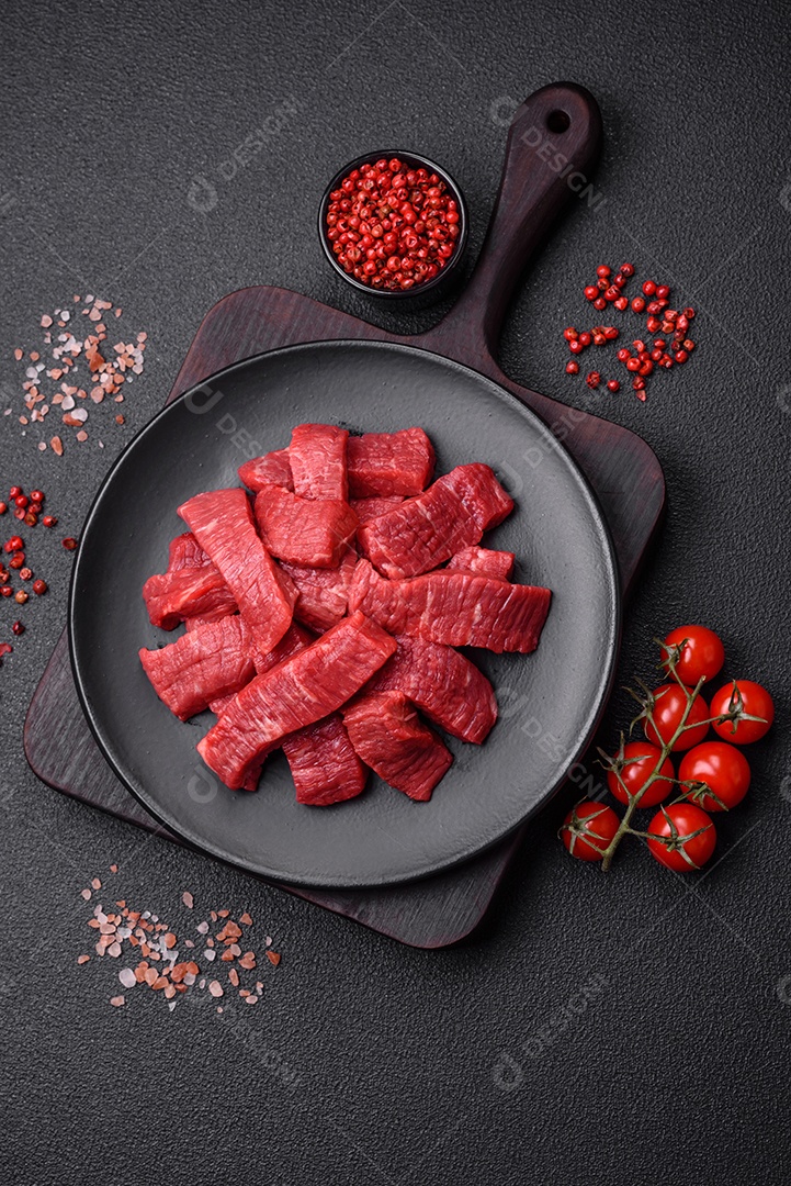 Fatias frescas e suculentas de carne crua com sal e especiarias sobre um fundo escuro de concreto