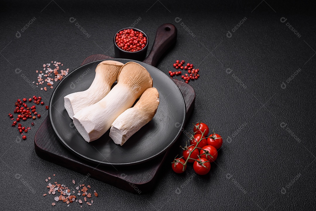 Cogumelos Pleurotus eryngii sobre um fundo escuro de concreto. Cogumelos comestíveis inteiros crus