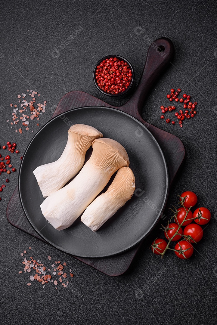 Cogumelos Pleurotus eryngii sobre um fundo escuro de concreto. Cogumelos comestíveis inteiros crus