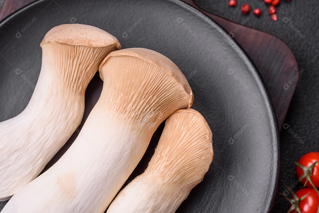 Cogumelos Pleurotus eryngii sobre um fundo escuro de concreto. Cogumelos comestíveis inteiros crus