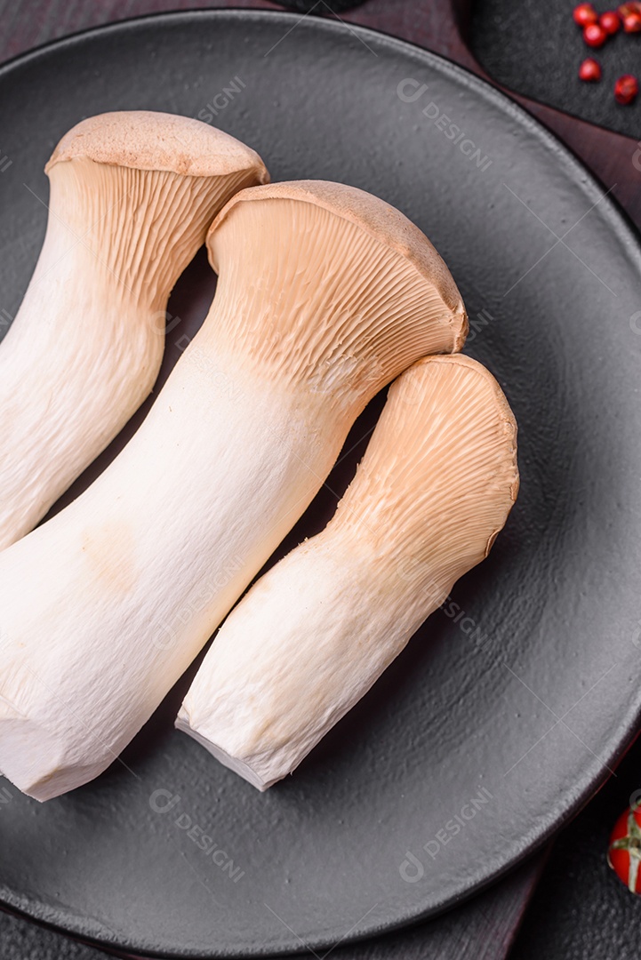 Cogumelos Pleurotus eryngii sobre um fundo escuro de concreto. Cogumelos comestíveis inteiros crus