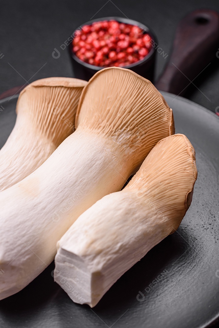 Cogumelos Pleurotus eryngii sobre um fundo escuro de concreto. Cogumelos comestíveis inteiros crus