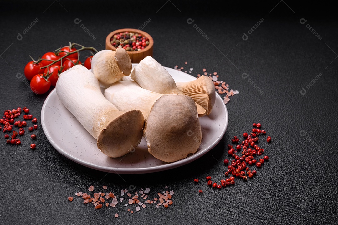 Cogumelos Pleurotus eryngii sobre um fundo escuro de concreto. Cogumelos comestíveis inteiros crus