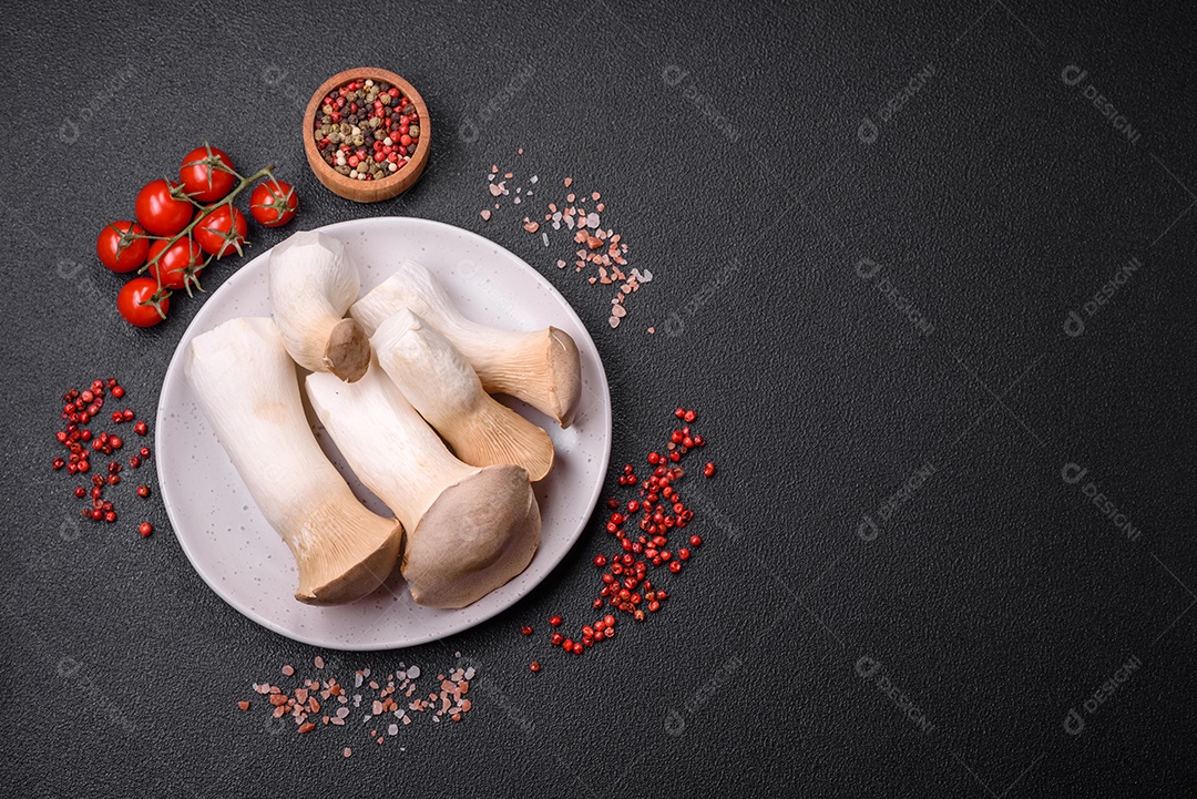 Cogumelos Pleurotus eryngii sobre um fundo escuro de concreto. Cogumelos comestíveis inteiros crus