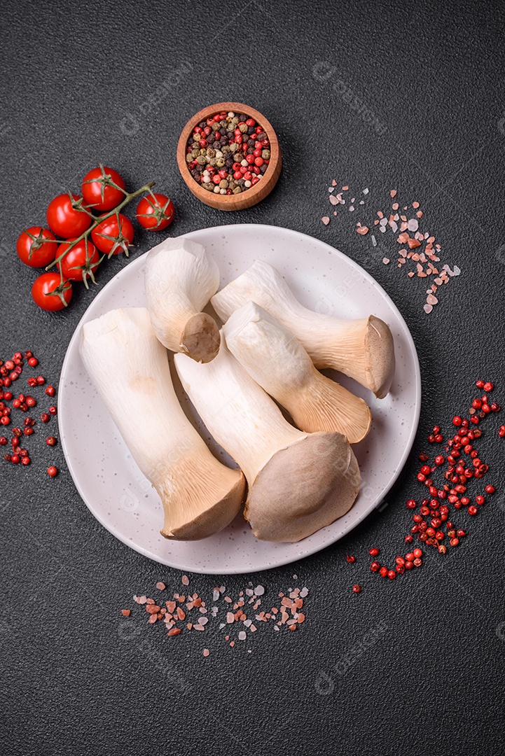 Cogumelos Pleurotus eryngii sobre um fundo escuro de concreto. Cogumelos comestíveis inteiros crus