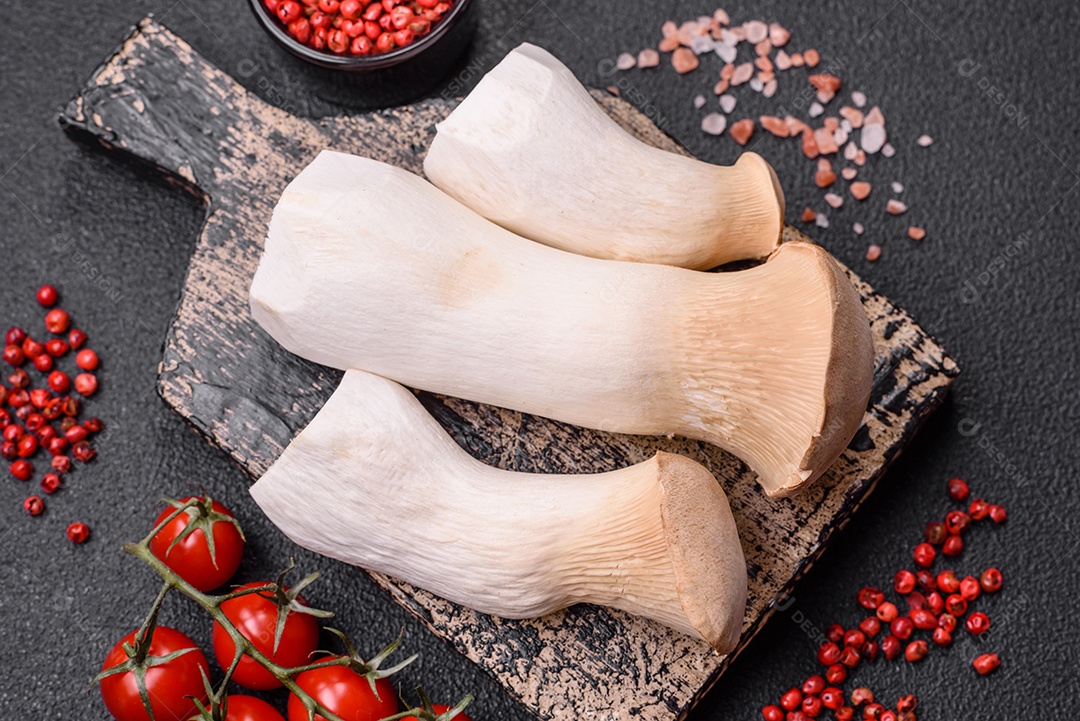 Cogumelos Pleurotus eryngii sobre um fundo escuro de concreto. Cogumelos comestíveis inteiros crus