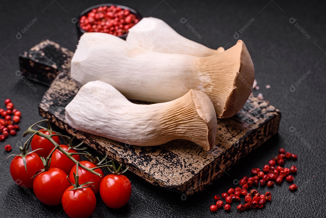 Cogumelos Pleurotus eryngii sobre um fundo escuro de concreto. Cogumelos comestíveis inteiros crus