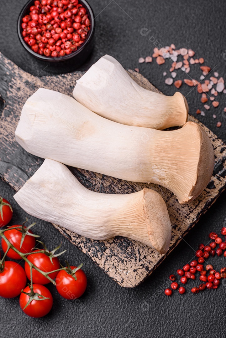 Cogumelos Pleurotus eryngii sobre um fundo escuro de concreto. Cogumelos comestíveis inteiros crus