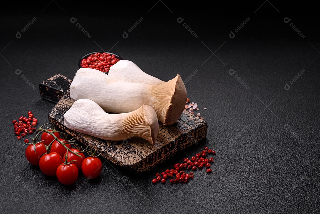 Cogumelos Pleurotus eryngii sobre um fundo escuro de concreto. Cogumelos comestíveis inteiros crus