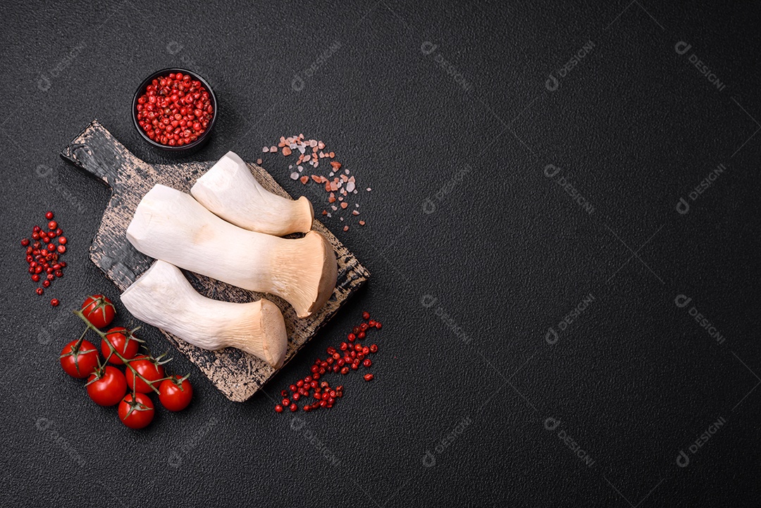 Cogumelos Pleurotus eryngii sobre um fundo escuro de concreto. Cogumelos comestíveis inteiros crus