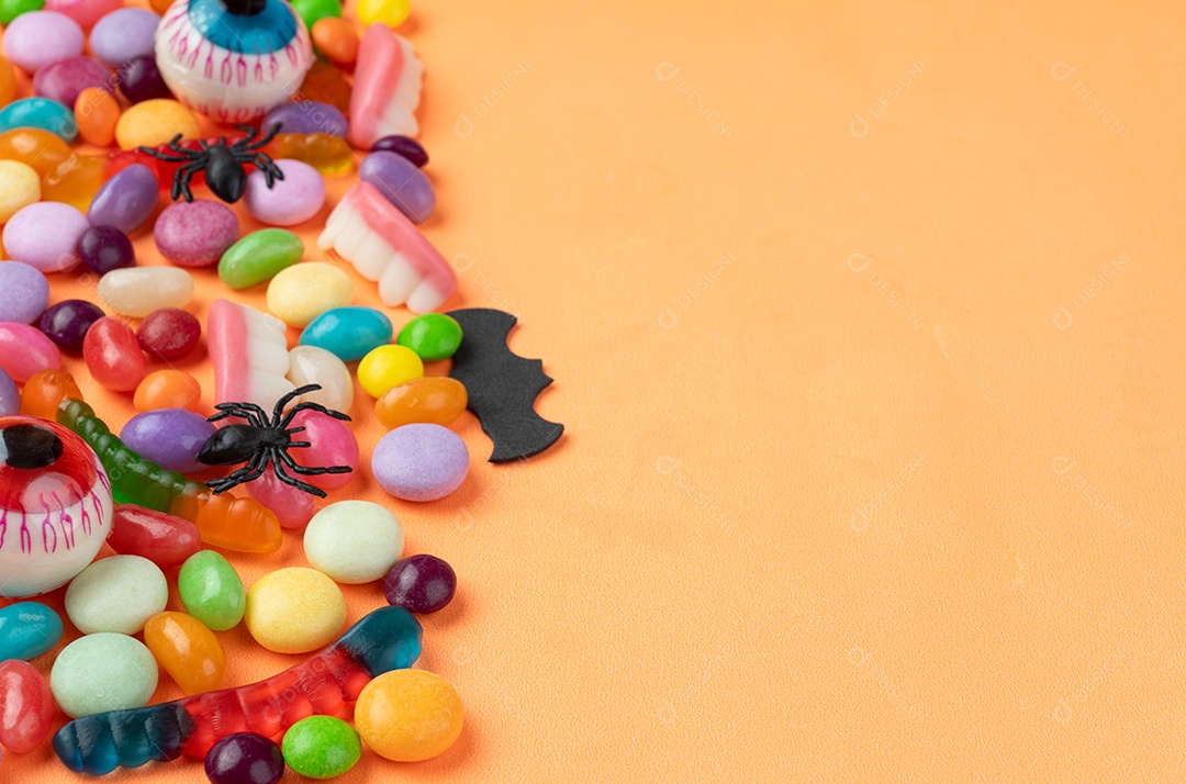 Doces coloridos sobre fundo laranja com espaço de cópia.