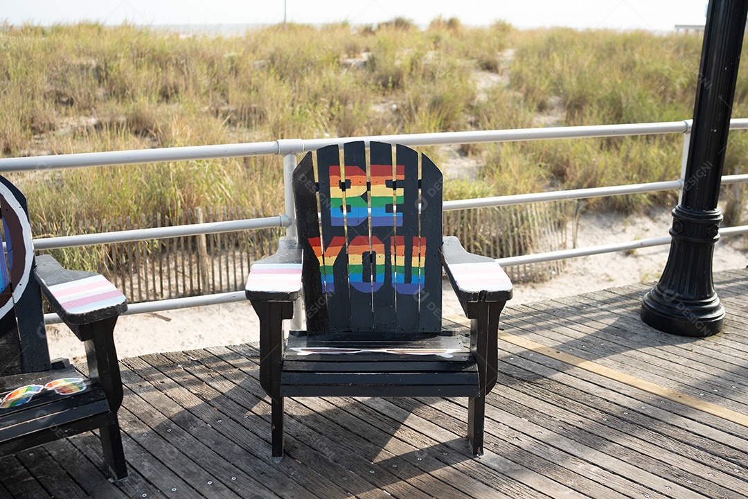 Cadeira sobre um piso de madeira escrito seja você com cores LGBT