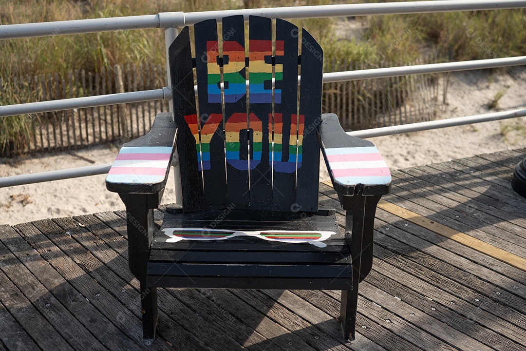 Cadeira sobre um piso de madeira escrito seja você com cores LGBT
