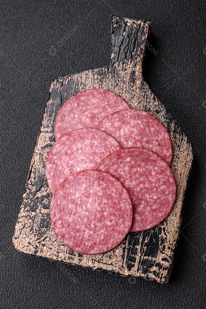 Deliciosa salsicha fresca fumada com sal e especiarias cortadas em fatias sobre um fundo escuro de concreto