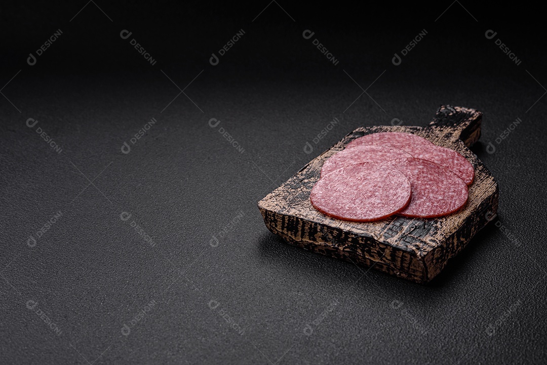 Deliciosa salsicha fresca fumada com sal e especiarias cortadas em fatias sobre um fundo escuro de concreto