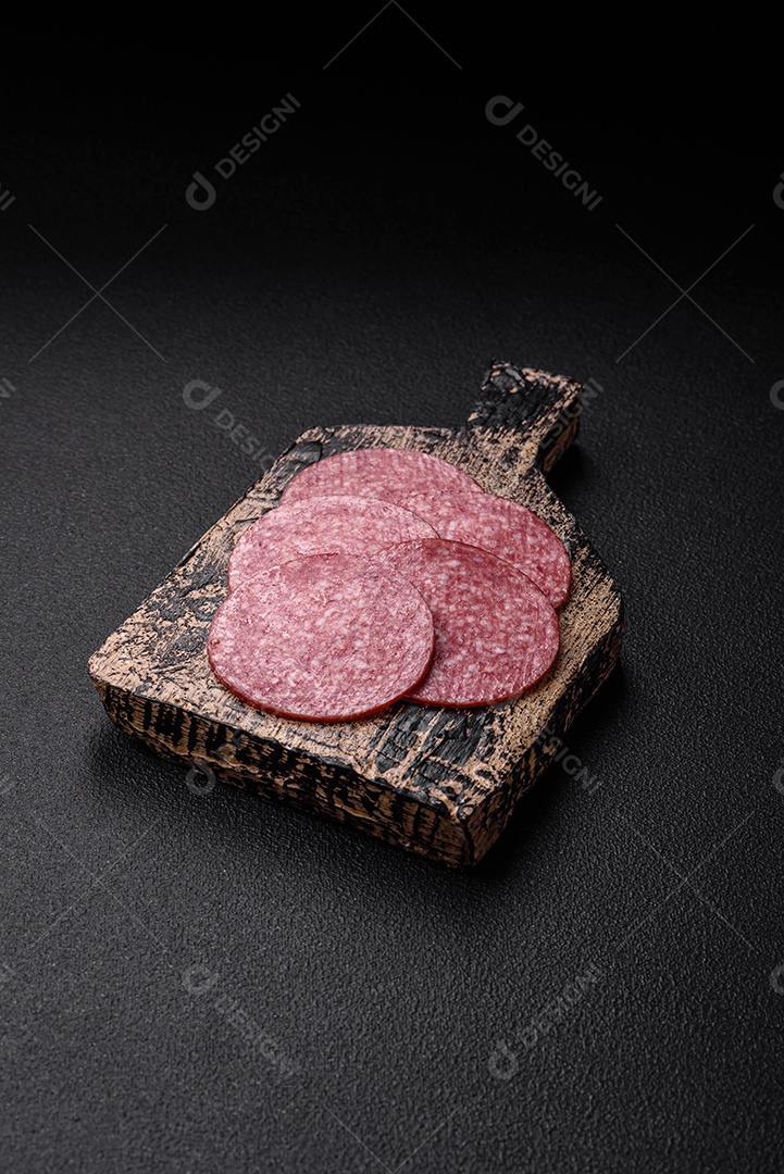 Deliciosa salsicha fresca fumada com sal e especiarias cortadas em fatias sobre um fundo escuro de concreto