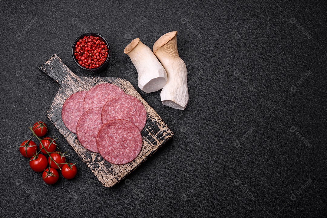 Deliciosa salsicha fresca fumada com sal e especiarias cortadas em fatias sobre um fundo escuro de concreto