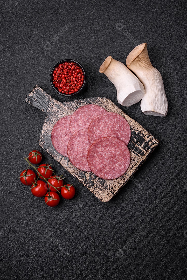 Deliciosa salsicha fresca fumada com sal e especiarias cortadas em fatias sobre um fundo escuro de concreto