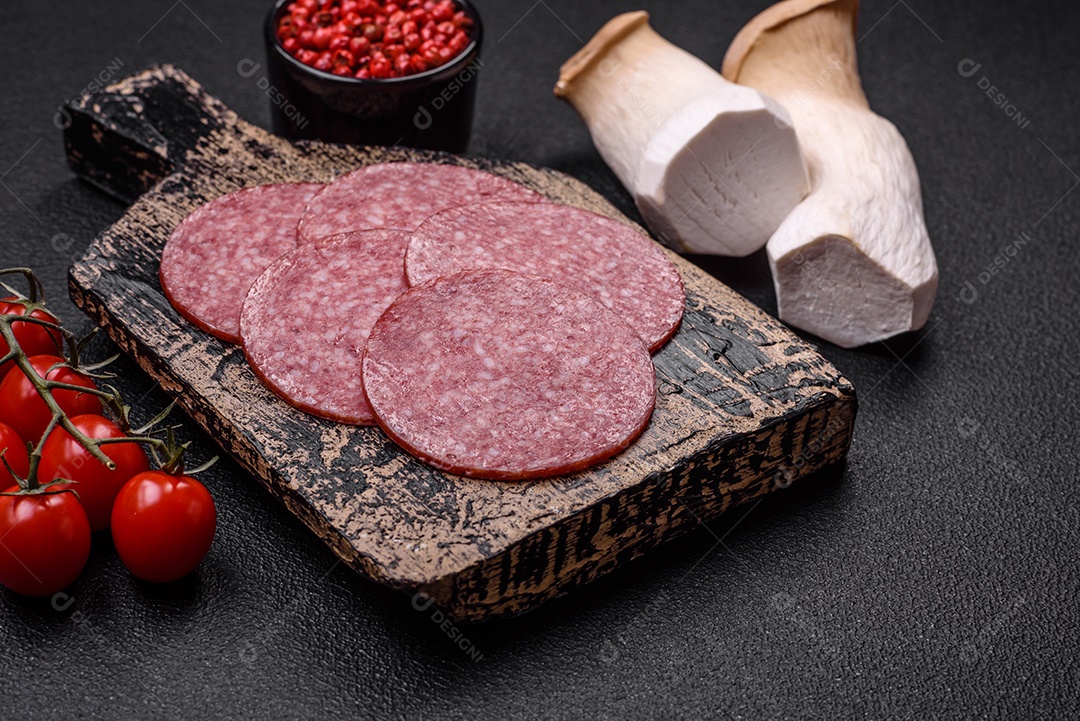 Deliciosa salsicha fresca fumada com sal e especiarias cortadas em fatias sobre um fundo escuro de concreto