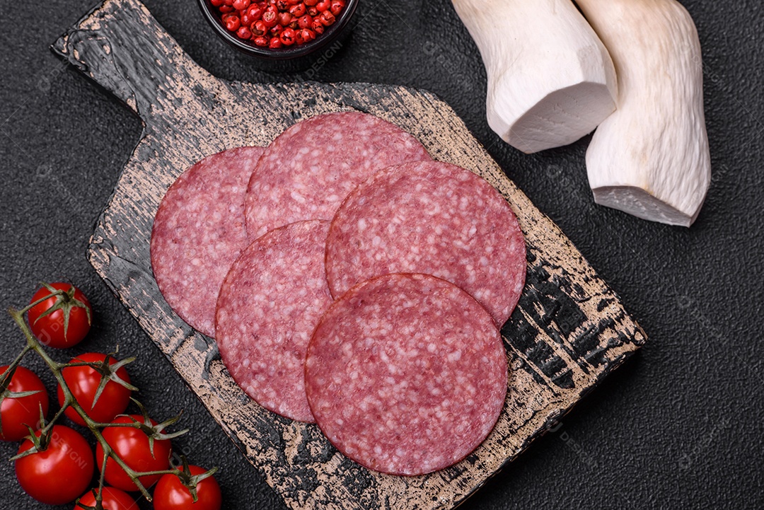 Deliciosa salsicha fresca fumada com sal e especiarias cortadas em fatias sobre um fundo escuro de concreto