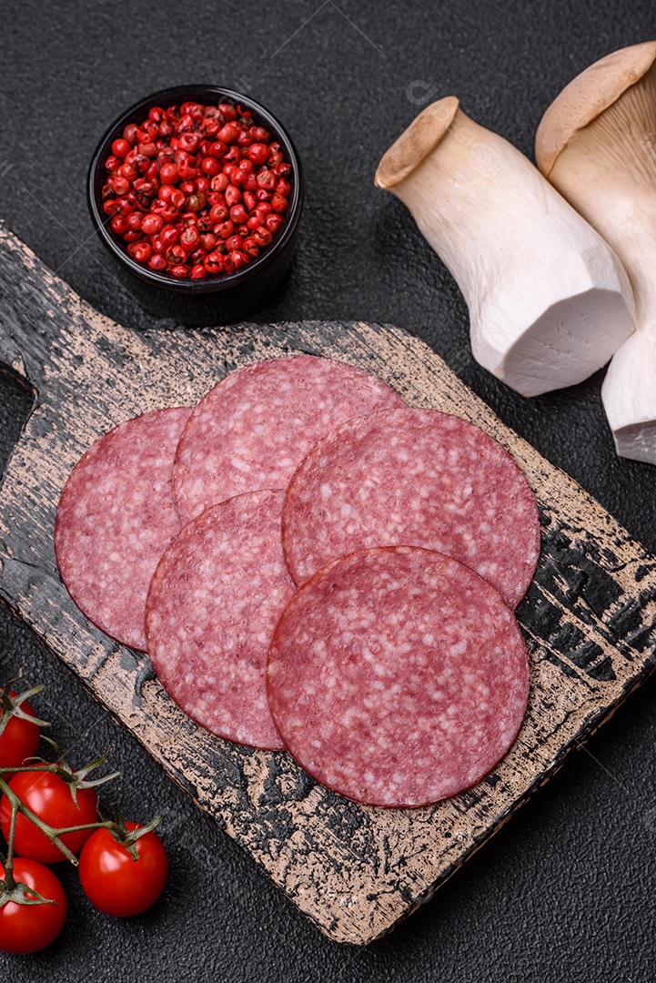 Deliciosa salsicha fresca fumada com sal e especiarias cortadas em fatias sobre um fundo escuro de concreto