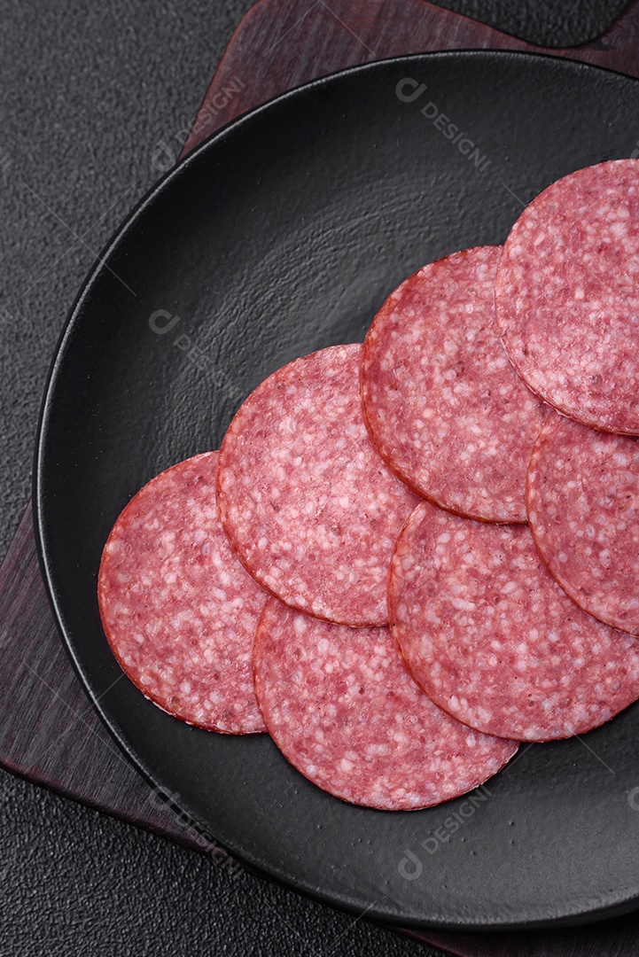 Deliciosa salsicha fresca fumada com sal e especiarias cortadas em fatias sobre um fundo escuro de concreto