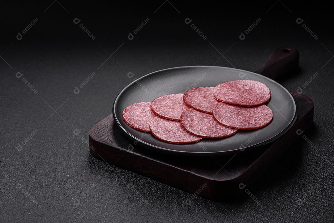 Deliciosa salsicha fresca fumada com sal e especiarias cortadas em fatias sobre um fundo escuro de concreto