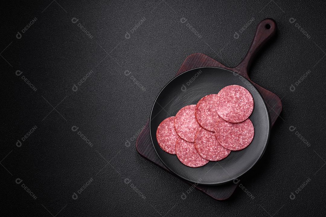 Deliciosa salsicha fresca fumada com sal e especiarias cortadas em fatias sobre um fundo escuro de concreto