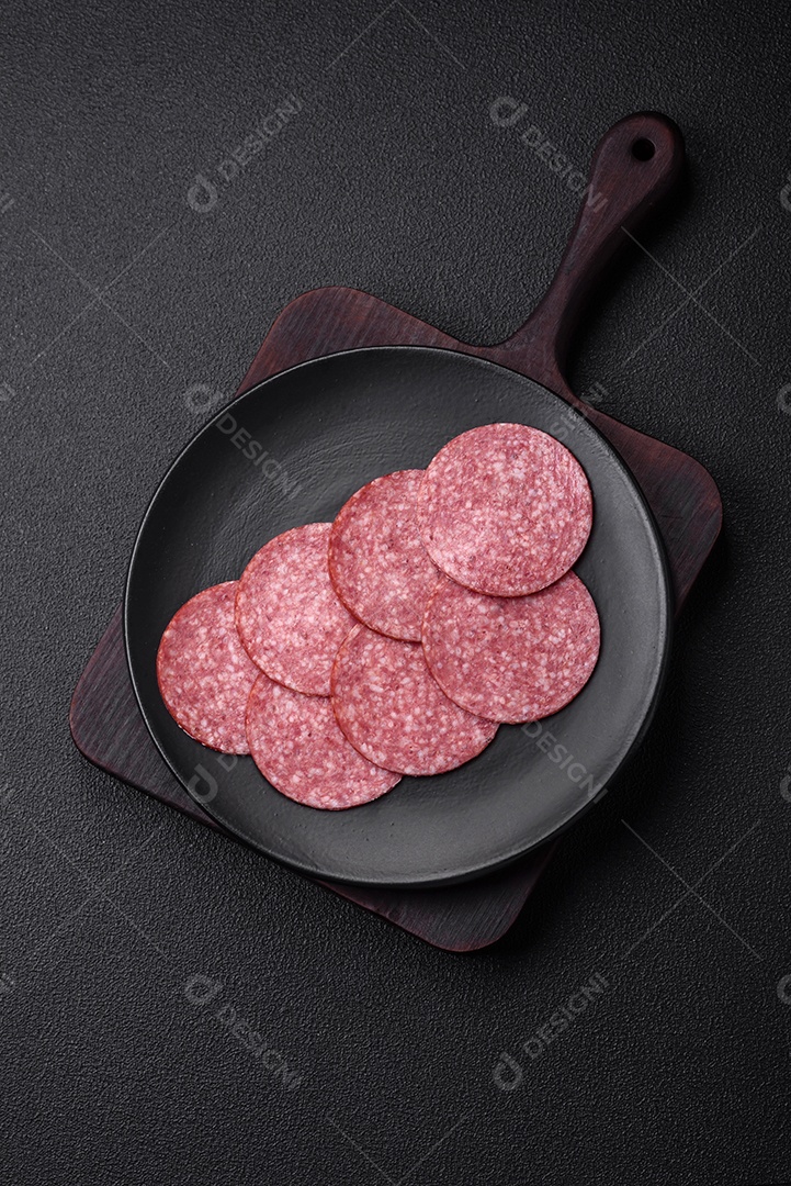 Deliciosa salsicha fresca fumada com sal e especiarias cortadas em fatias sobre um fundo escuro de concreto