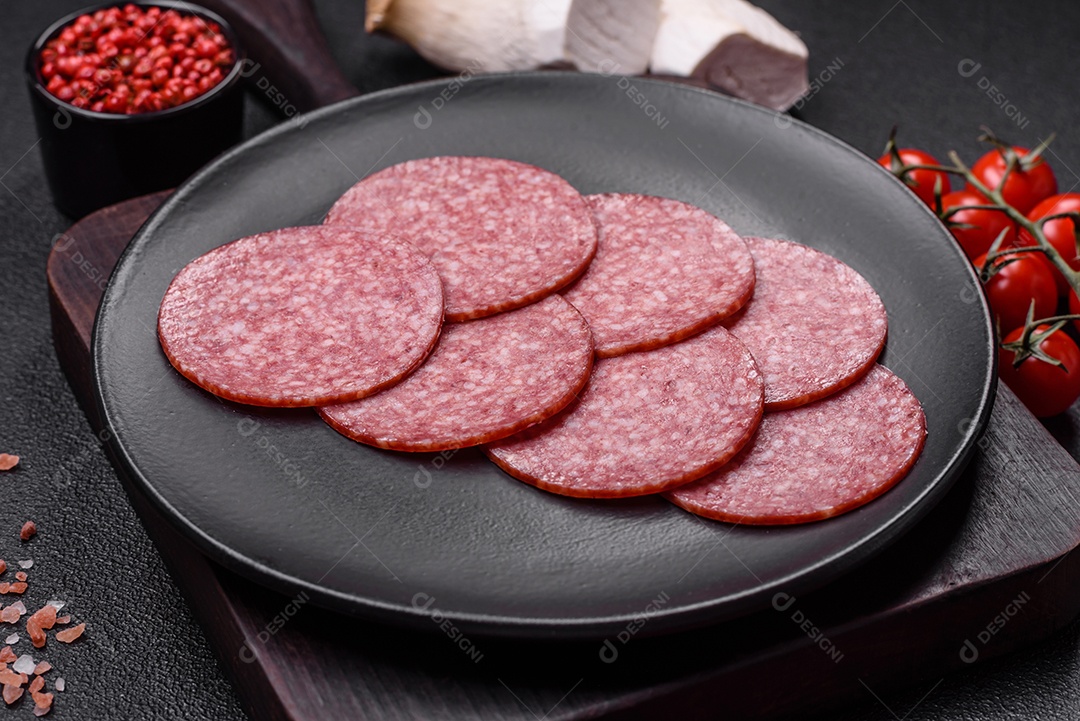 Deliciosa salsicha fresca fumada com sal e especiarias cortadas em fatias sobre um fundo escuro de concreto