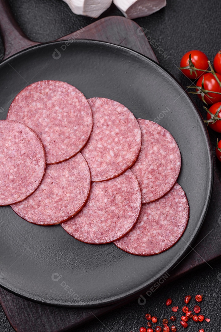 Deliciosa salsicha fresca fumada com sal e especiarias cortadas em fatias sobre um fundo escuro de concreto