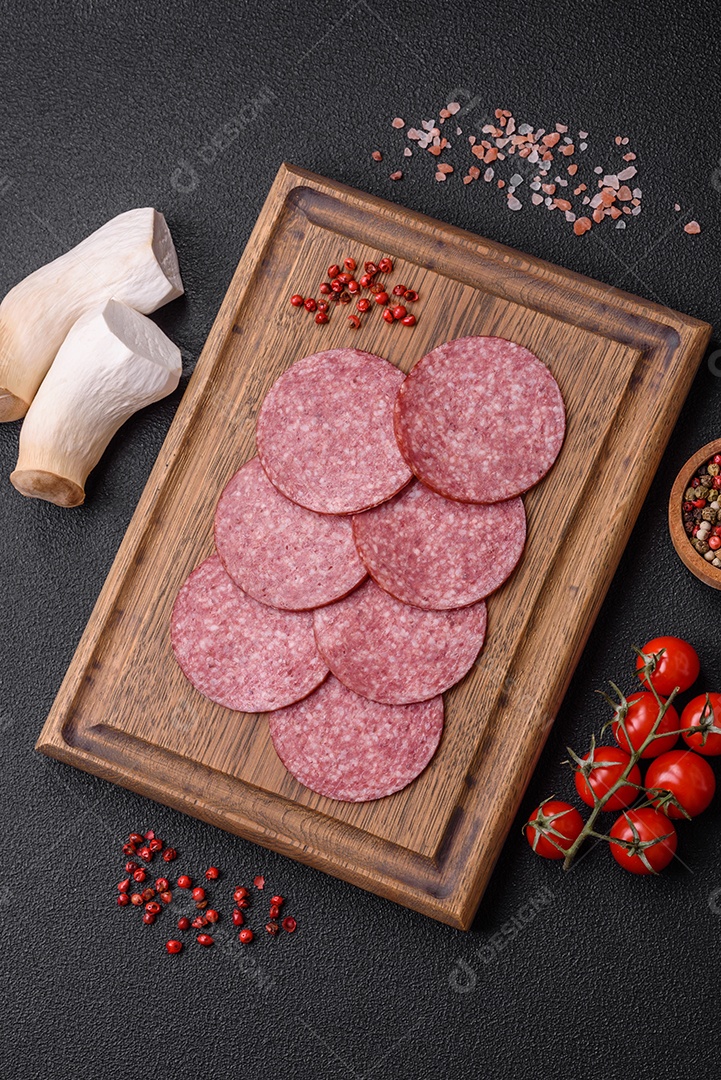 Deliciosa salsicha fresca fumada com sal e especiarias cortadas em fatias sobre um fundo escuro de concreto