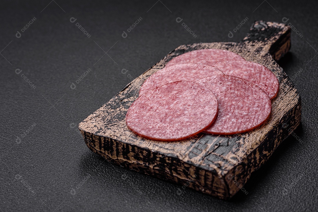 Deliciosas fatias de batata frita crocante com sal, especiarias e ervas sobre um fundo escuro de concreto