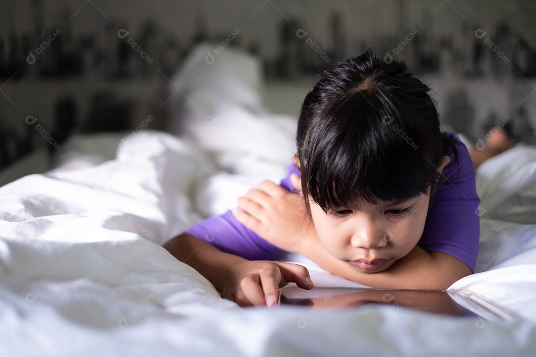 Linda garotinha deitada usando tablet