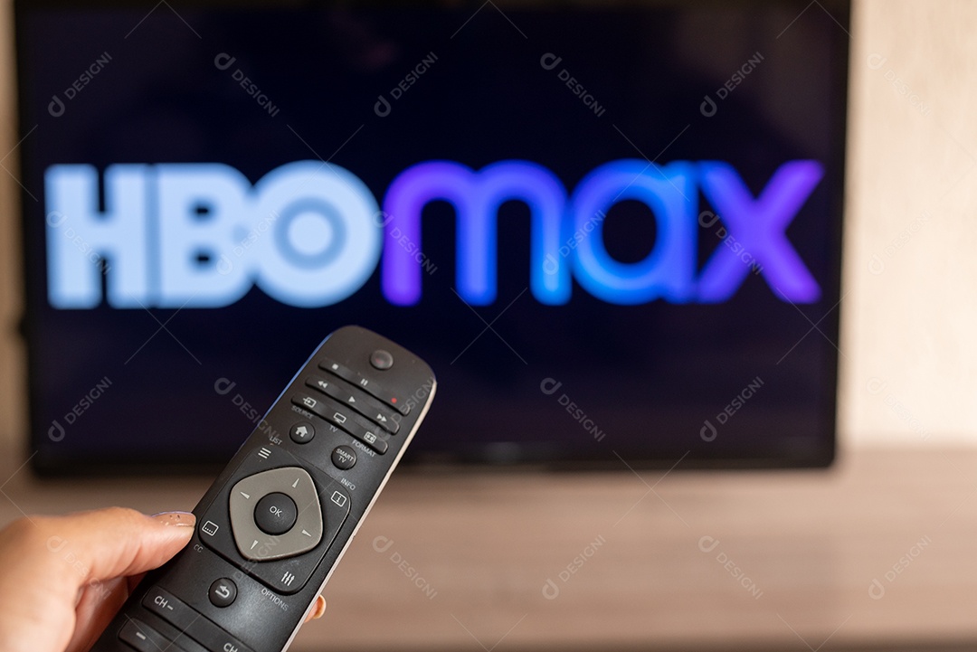 Mão com controle da tv de tela plana exibindo o logotipo da HBO Max