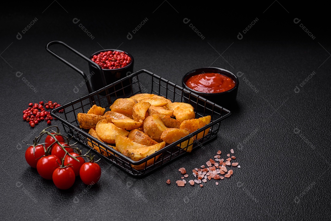 Deliciosas fatias de batata frita crocante com sal, especiarias e ervas sobre um fundo escuro de concreto