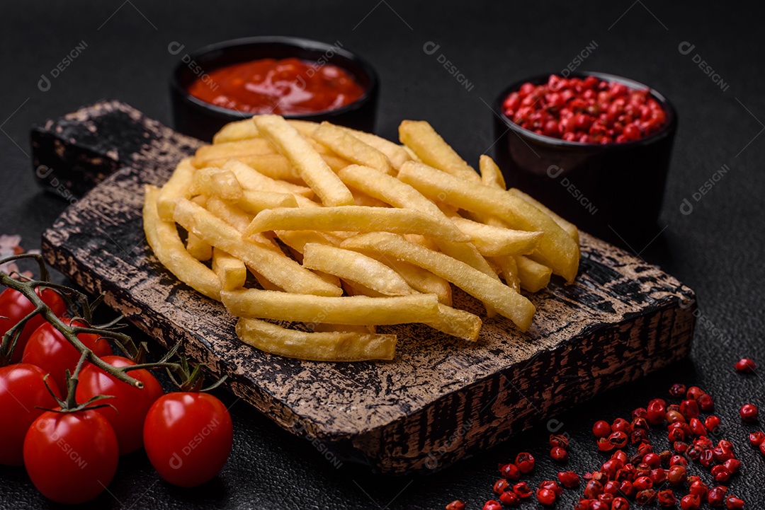 Deliciosas fatias de batata frita crocante com sal, especiarias e ervas sobre um fundo escuro de concreto